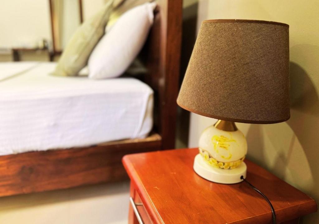 a lamp sitting on a table next to a bed at Osara Holiday Home in Anuradhapura