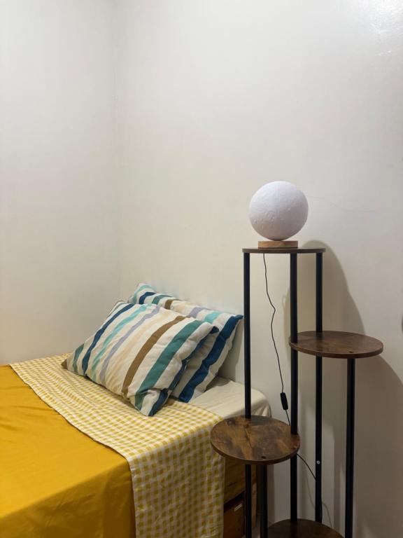 a bed with a yellow blanket and a lamp and two tables at RiDivingSpot Mabini in Mabini