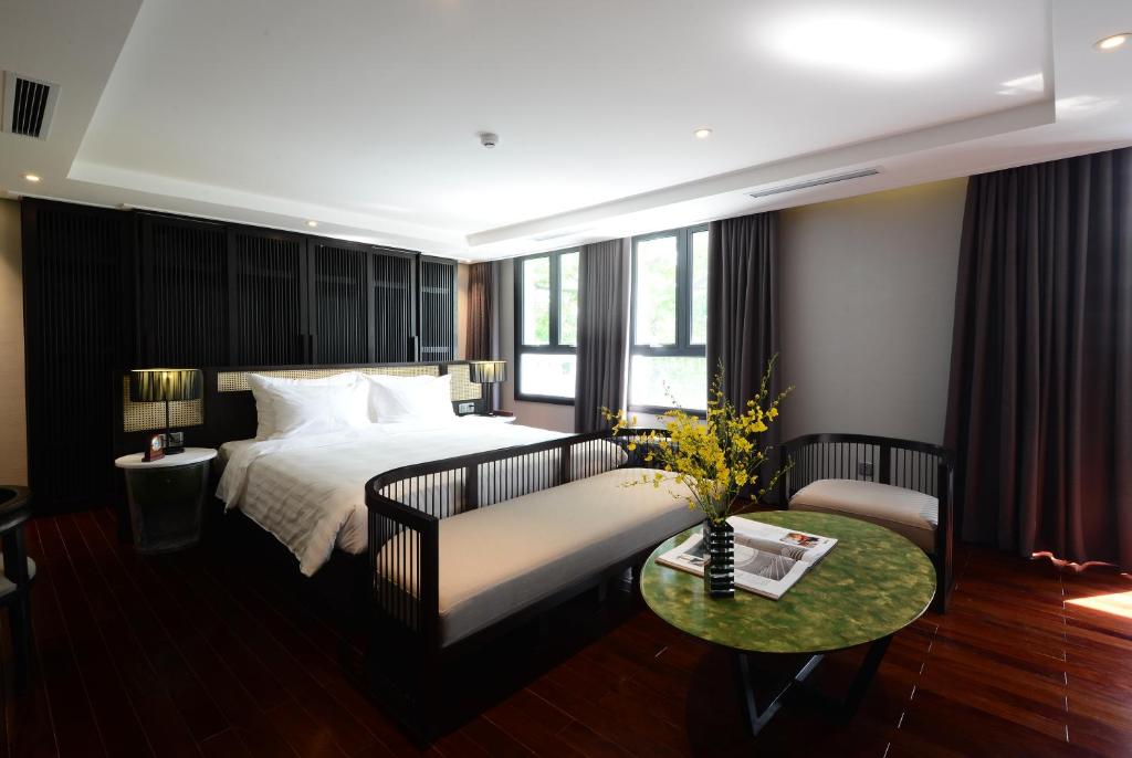 ein Schlafzimmer mit einem Bett, einem Sofa und einem Tisch in der Unterkunft The Chi Boutique Hotel in Hanoi