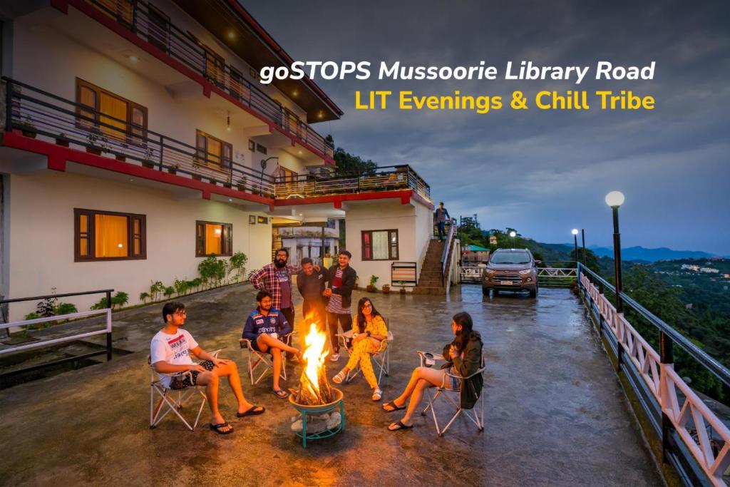 a group of people sitting around a fire outside a house at goSTOPS Mussoorie, Library Road in Mussoorie
