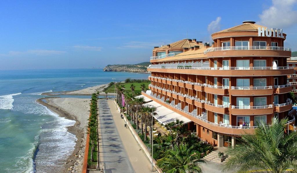 a building on the beach next to the ocean at Sunway Playa Golf & Spa Sitges in Sitges