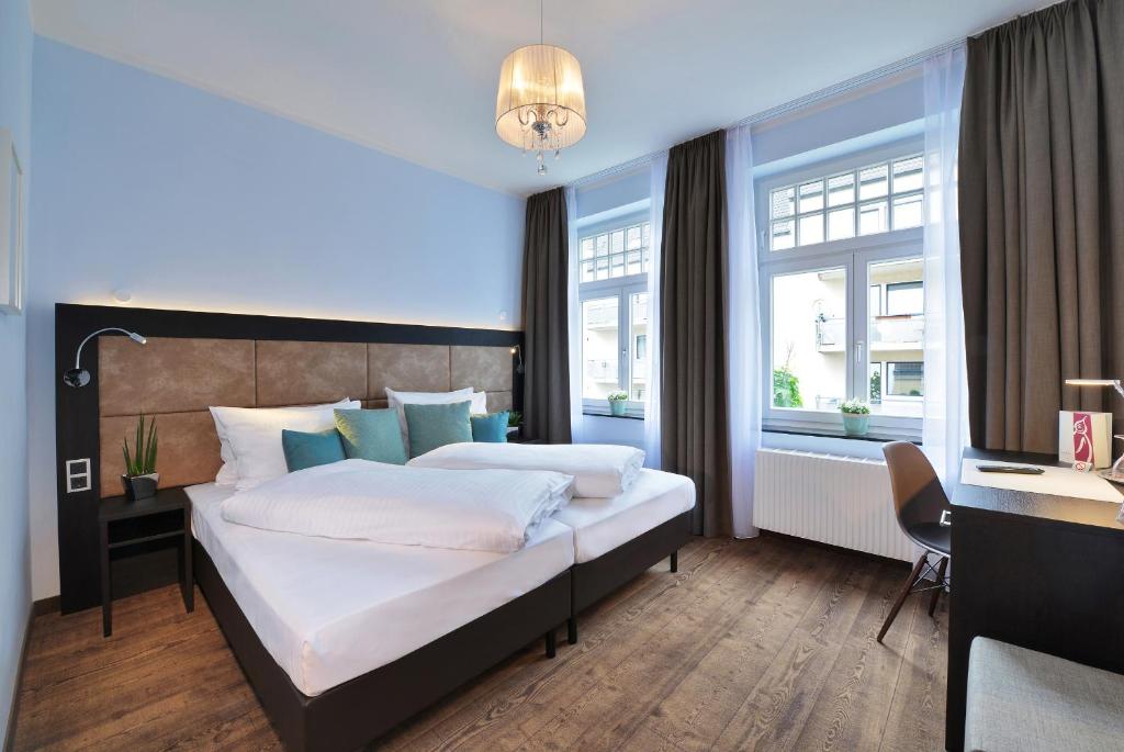 um quarto com uma cama, uma secretária e janelas em UHU Gästehaus Superior em Colônia