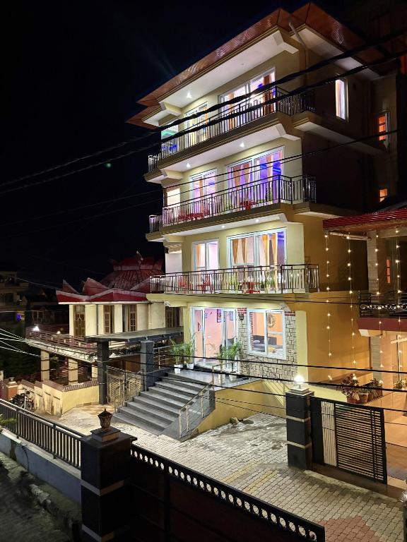 a large building with stairs in front of it at night at Serene Vista Dharamshala in Dharmsāla