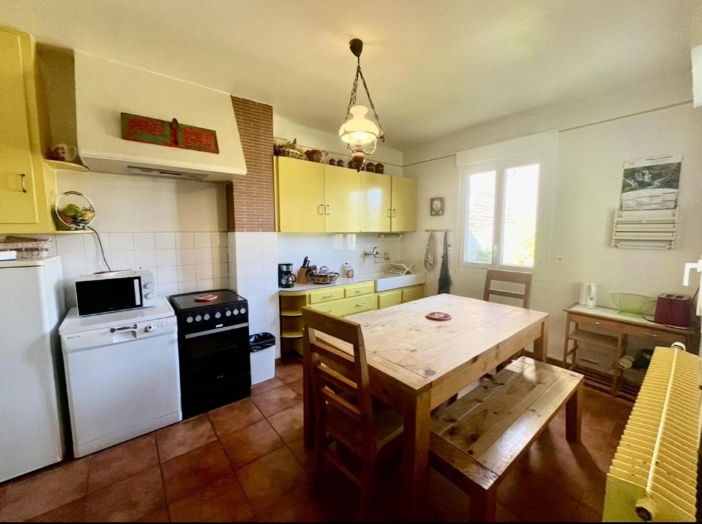 a kitchen with a wooden table and a white refrigerator at les chaussons d'arlequine in Dompierre-sur-Besbre