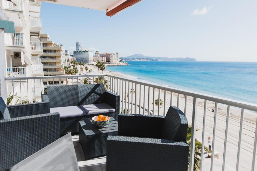 Un balcón con sillas y vista a la playa. en Front line beach location with stunning ocean view, en Ifach