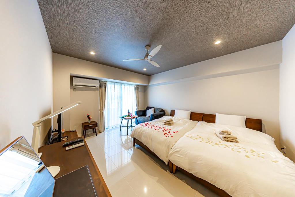 een slaapkamer met een groot bed en een televisie bij 真栄田岬グランブルー 104 in Onna