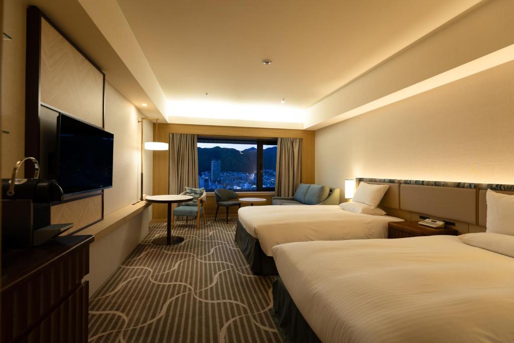 a hotel room with two beds and a flat screen tv at Hotel Okura Kobe in Kobe