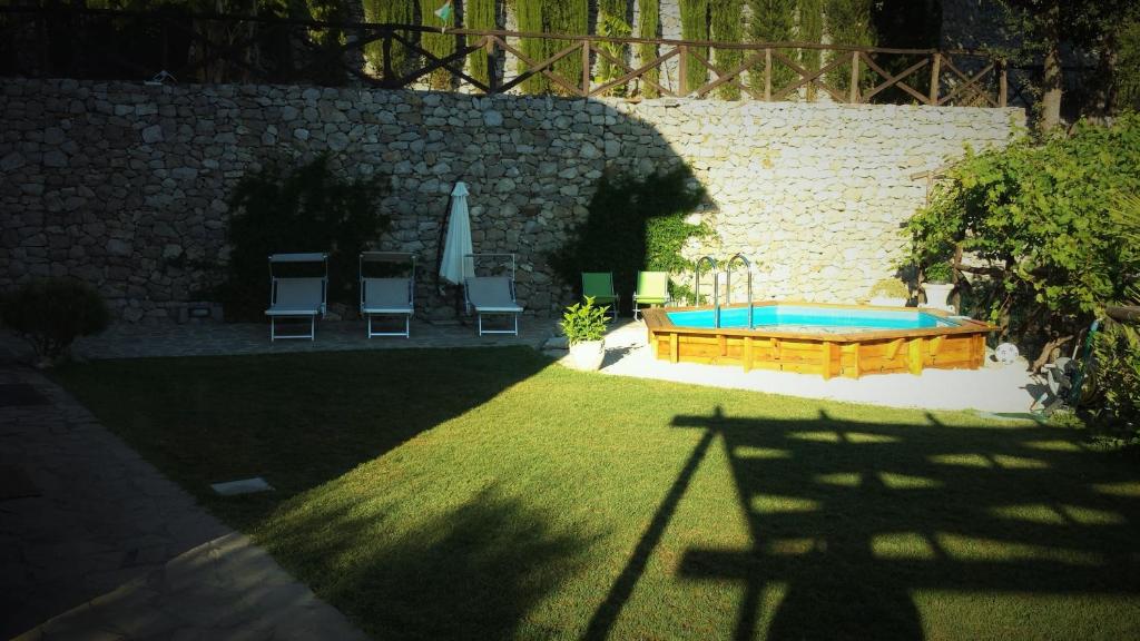 a backyard with a swimming pool and chairs and a wall at Villa Talea in SantʼAgata sui Due Golfi