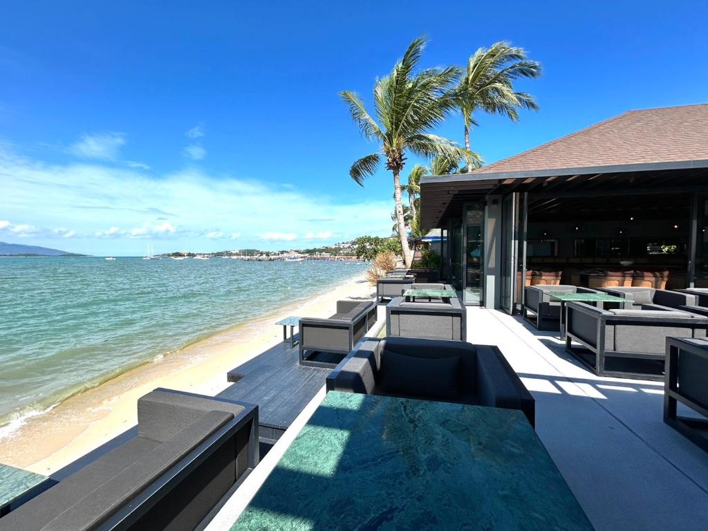 ein Resort mit Tischen und Stühlen am Strand in der Unterkunft Transit Samui Resort in Koh Samui 