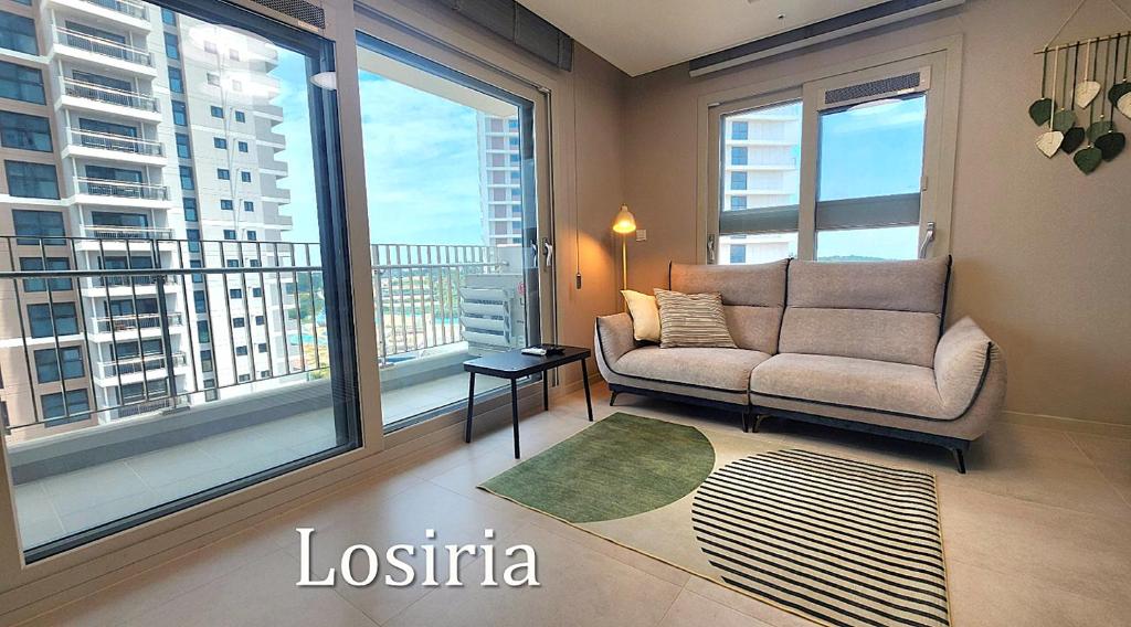 a living room with a couch and a large window at Busan Osiria Residence Losiria in Busan