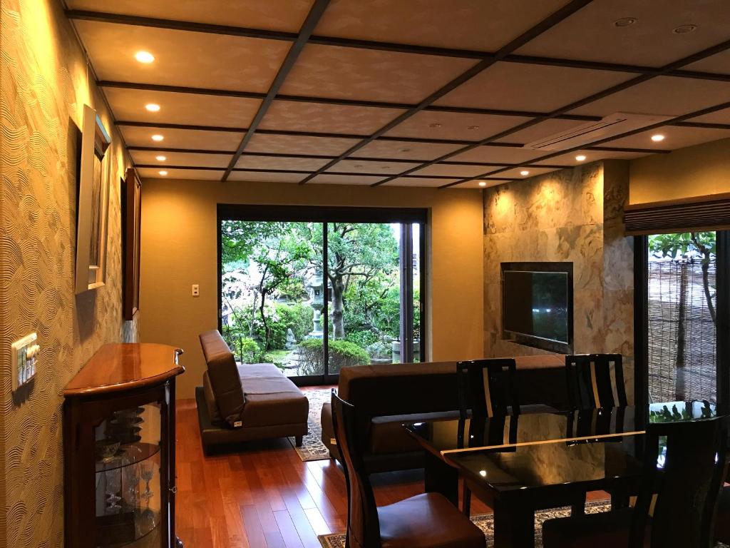 a living room with a table and chairs and a television at Hananobou Kinkakuji-michi in Kyoto