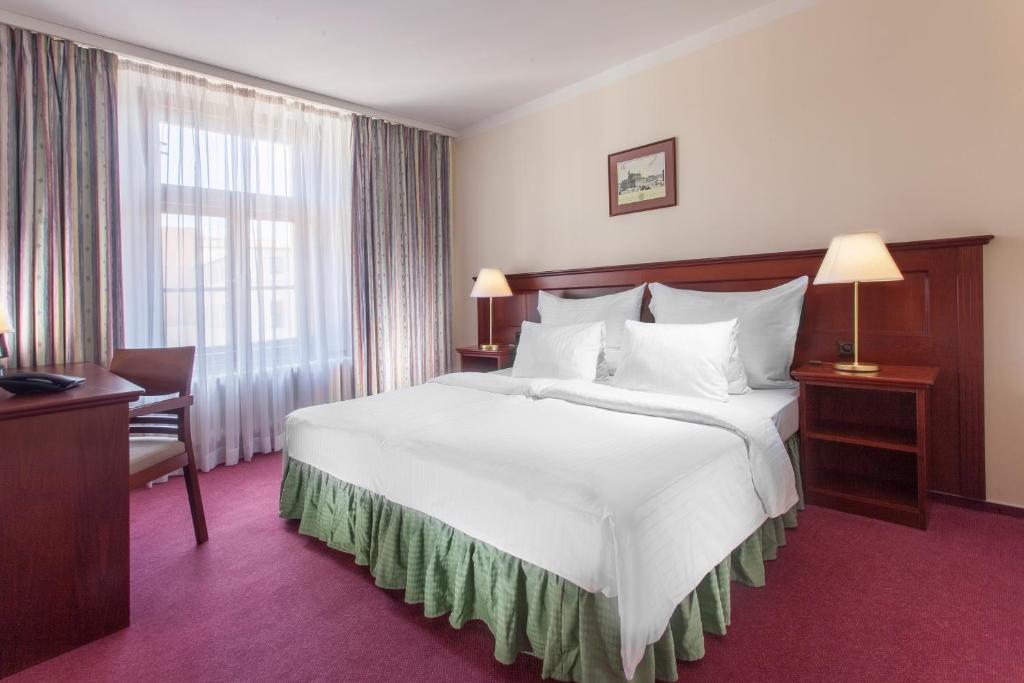 um quarto de hotel com uma grande cama branca e uma janela em Hotel Lunik em Praga