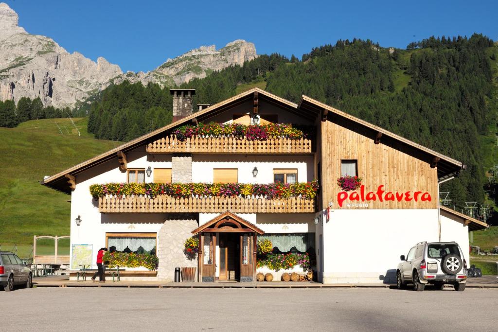 un edificio con dei fiori sul lato di Rifugio Palafavera a Zoldo Alto