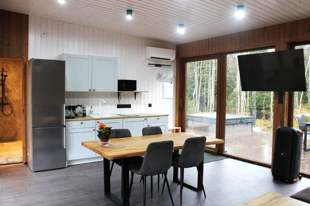 a kitchen with a table and chairs and a refrigerator at Metsamajake Hubert sauna ja mullivanniga looduse keskel in Sigula