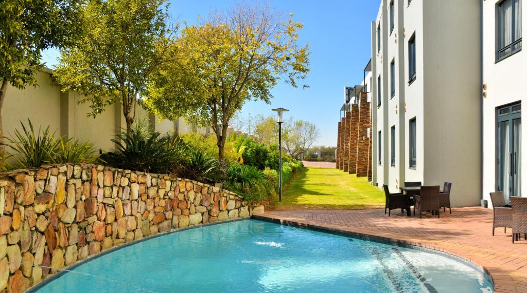 una piscina junto a una pared de piedra en Premier Hotel Midrand, en Midrand