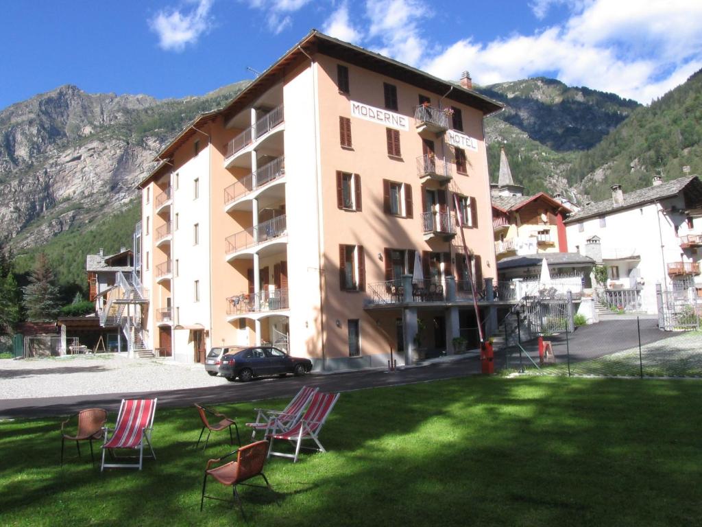 a building with chairs in the grass in front of it at Residence Hotel Moderno in Gaby