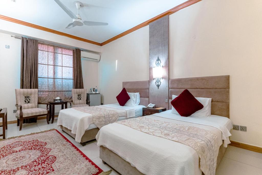 a hotel room with two beds and a table at Shelton's Rezidor Peshawar in Peshawar