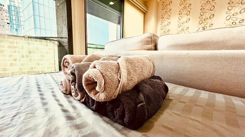 Cette chambre comprend un canapé et un lit avec des serviettes. dans l'établissement Noble Remix Thonglor - Direct BTS Access - Super Fast Wi-Fi, à Bangkok