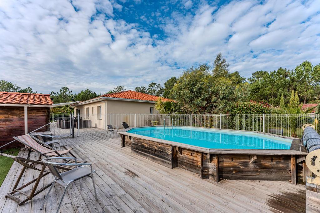 una piscina en una terraza de madera junto a una casa en Villa piscine entre lac et océan, en Cazaux