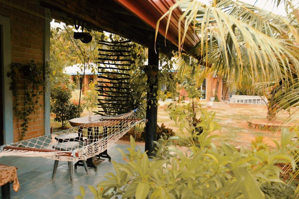 a porch with a hammock and a table in a garden at Birds of Paradise Surf and Yoga Boutique & Retreat in Weligama