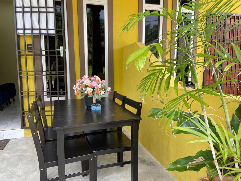 a black table with flowers on it in front of a building at Homestay Sri Aliff in Sri Gading