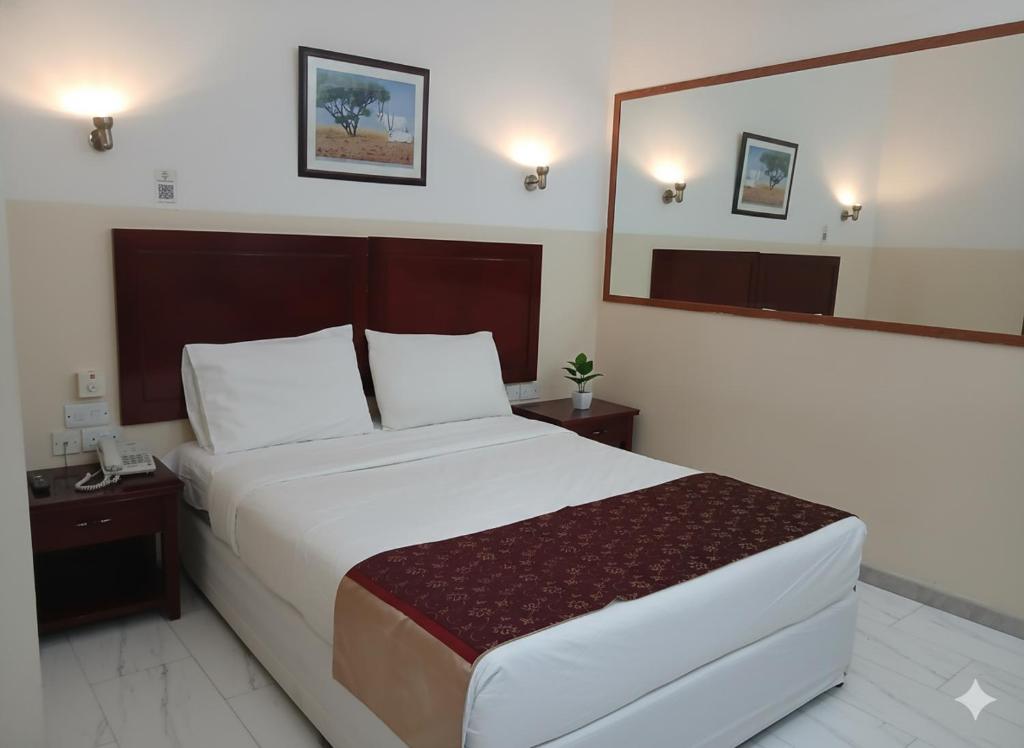 Un dormitorio con una cama grande y un espejo grande. en Makran Palace Hotel, en Ma‘ābīlah