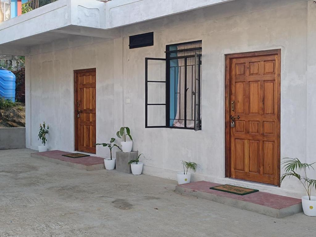 a house with two doors and potted plants on it at PHL homestay in Pynursla