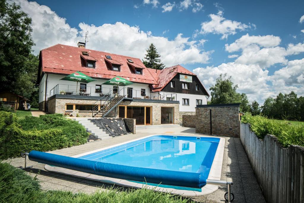 a house with a swimming pool in front of it at Penzion Ekosport in Stachy