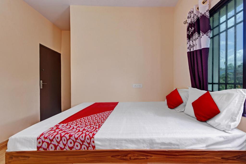 a bedroom with a large bed with red and white pillows at Hotel O The Harsa Inn in Sānkchi