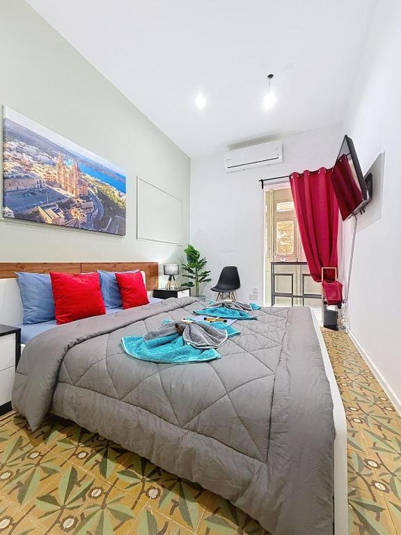 a bedroom with a large bed with red and blue pillows at Modern Studio Apartment1 next to Valletta in Il-Furjana