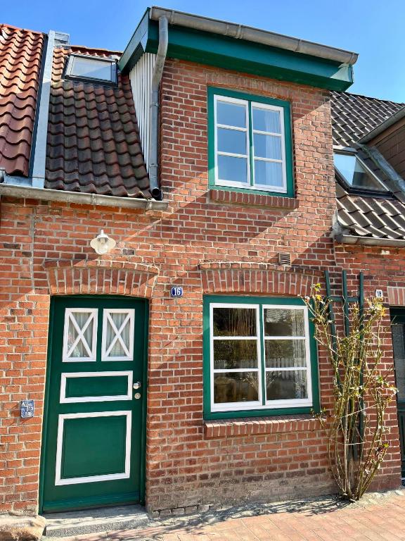 a brick house with a green door and two windows at Dat Lüttje in Fehmarn