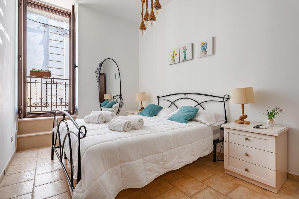 a bedroom with a bed with white sheets and blue pillows at Helios Vacanze in Conversano