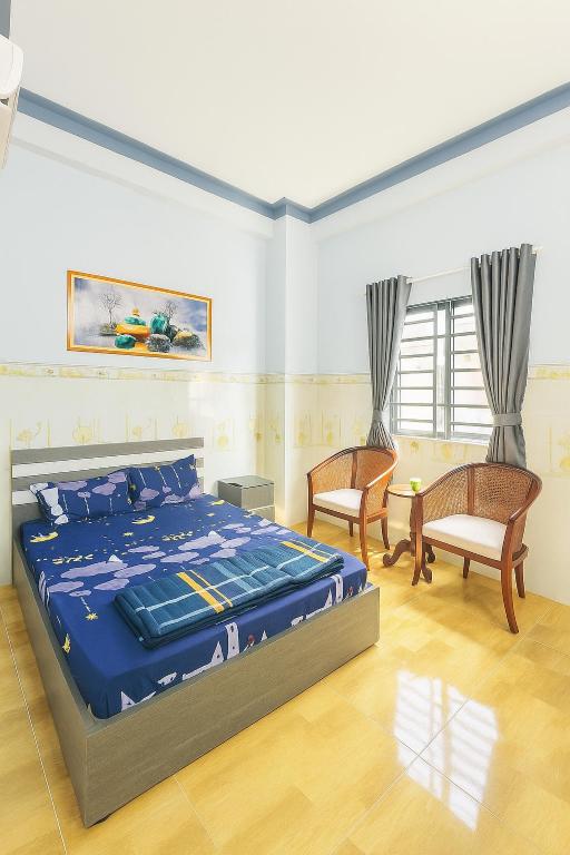 a bedroom with a bed and two chairs at Hoàng Gia 2 Motel Long An in Ðức Hòa