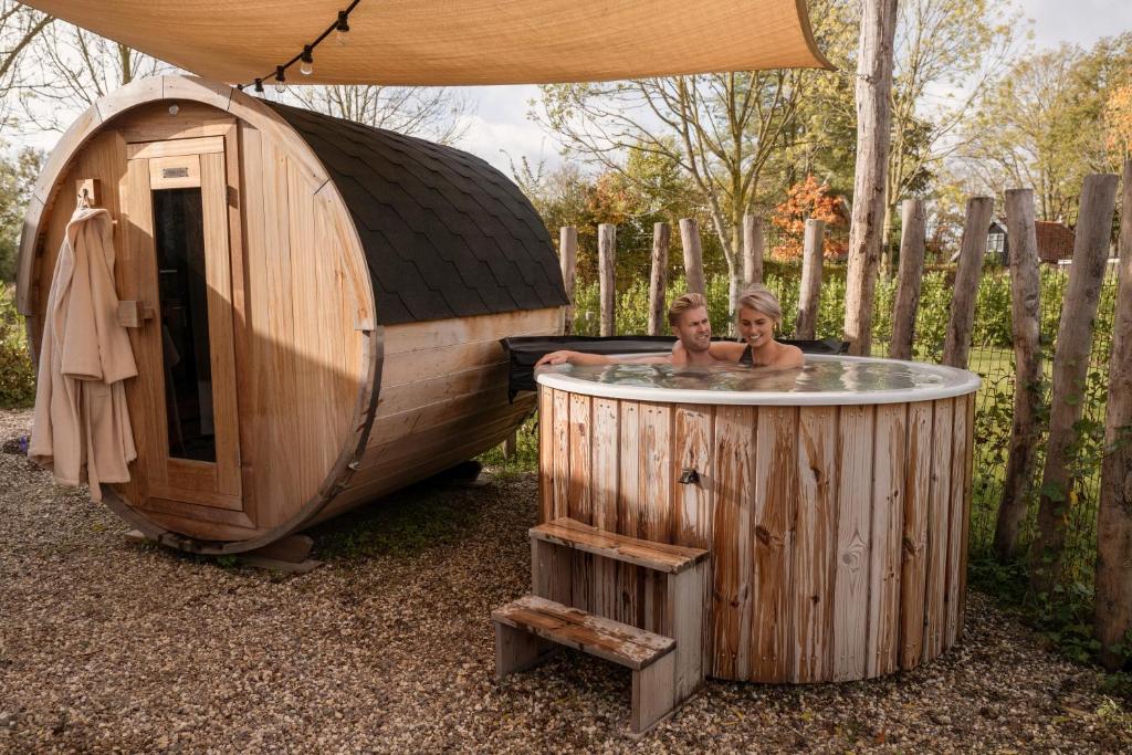 two children bathing in a hot tub next to a round wooden building at Hofparken Wiltershaar in Winterswijk