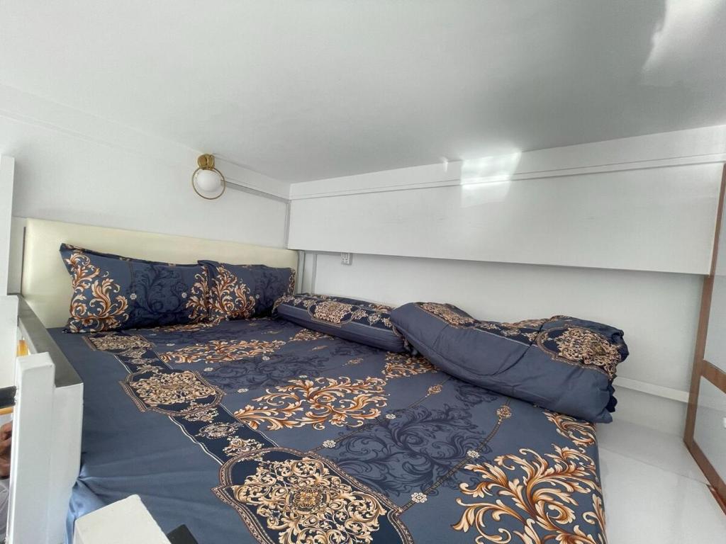 a small bedroom with a bed with blue and gold pillows at City & River Views near Royal Palace and Watphnom in Phnom Penh