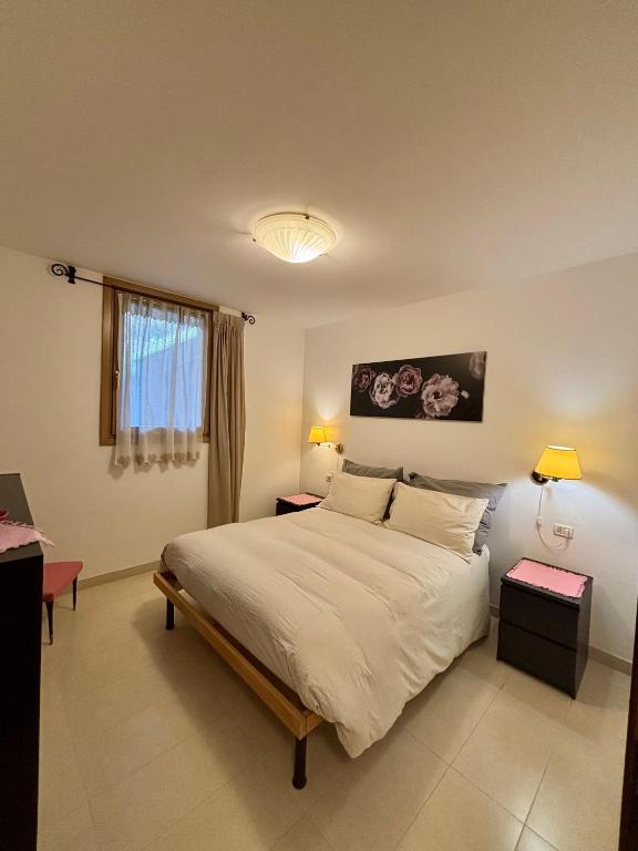 a bedroom with a large bed with two tables and two lamps at Pragma Apartments - Appartamento Dellantonio in Predazzo
