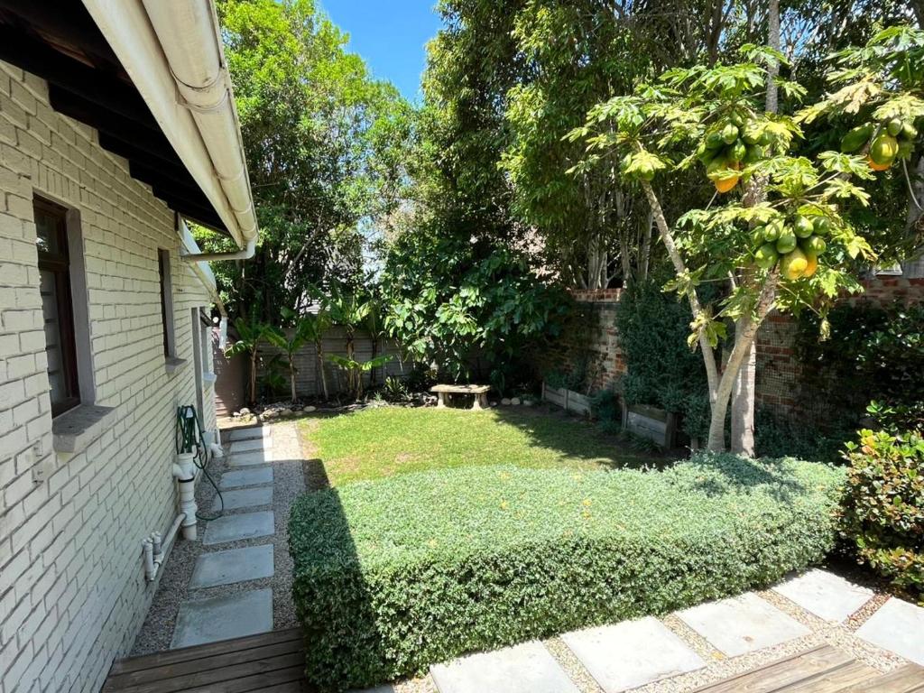 een tuin van een huis met een boom bij SeaSalt Rest in Plettenbergbaai