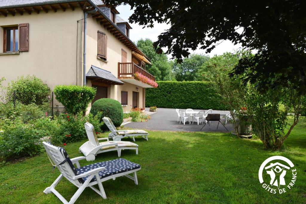 a yard with chairs and tables and a house at Le gîte du Puech de Fons in Le Cayrol