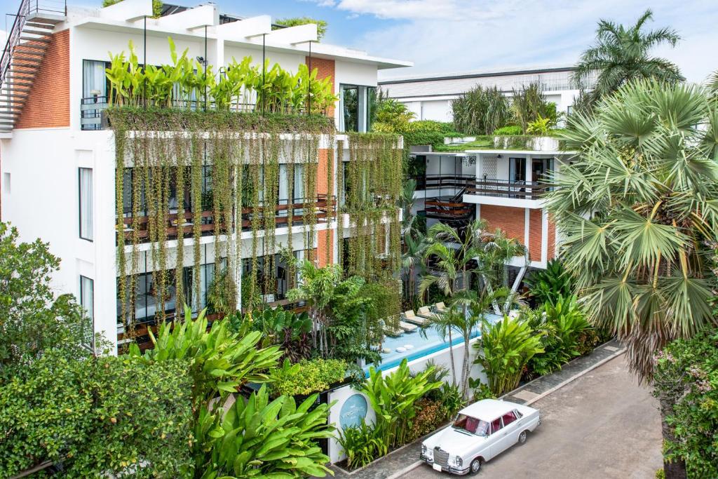 an apartment building with a garden with a car parked in front at Viroth's Villa in Siem Reap