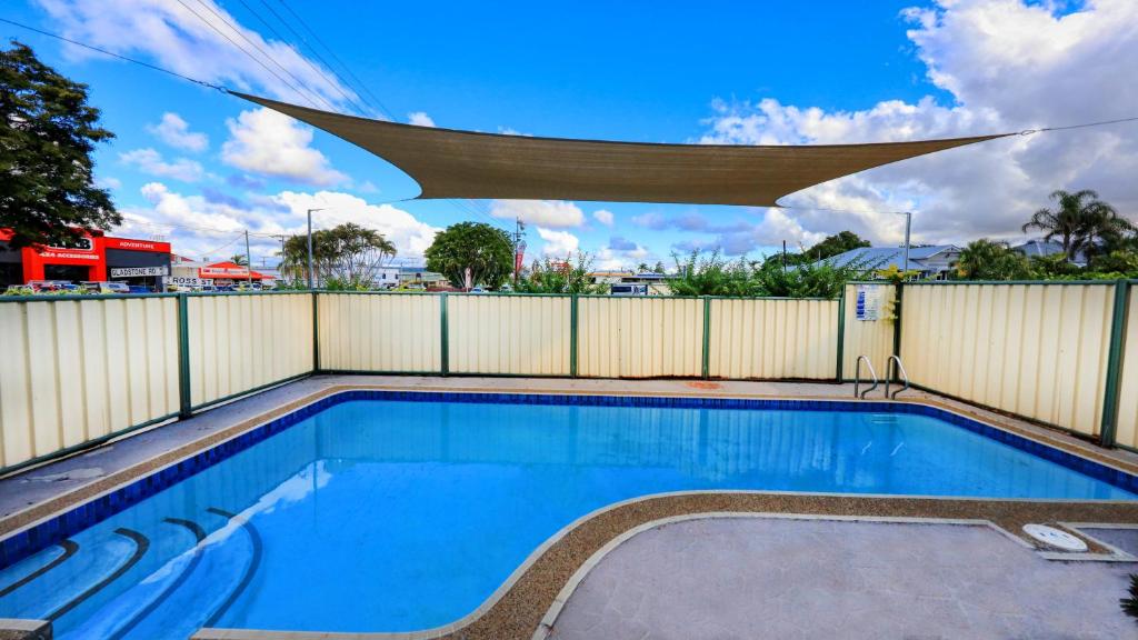 a swimming pool with a privacy fence and a swimming pool at Tropical Gateway Motor Inn in Rockhampton