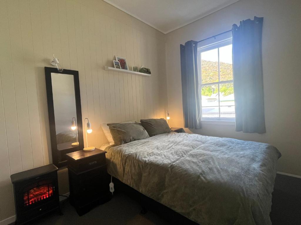 a bedroom with a bed and a mirror and a window at Nourish Reefton & Wilsons Hotel in Reefton