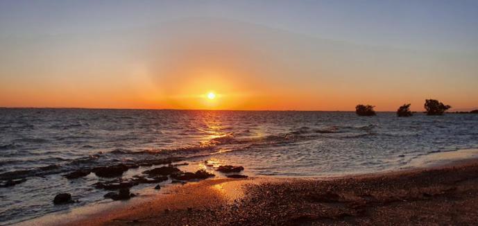um pôr do sol na praia com o sol se pondo em Palm dune Sanctuary em Nobk