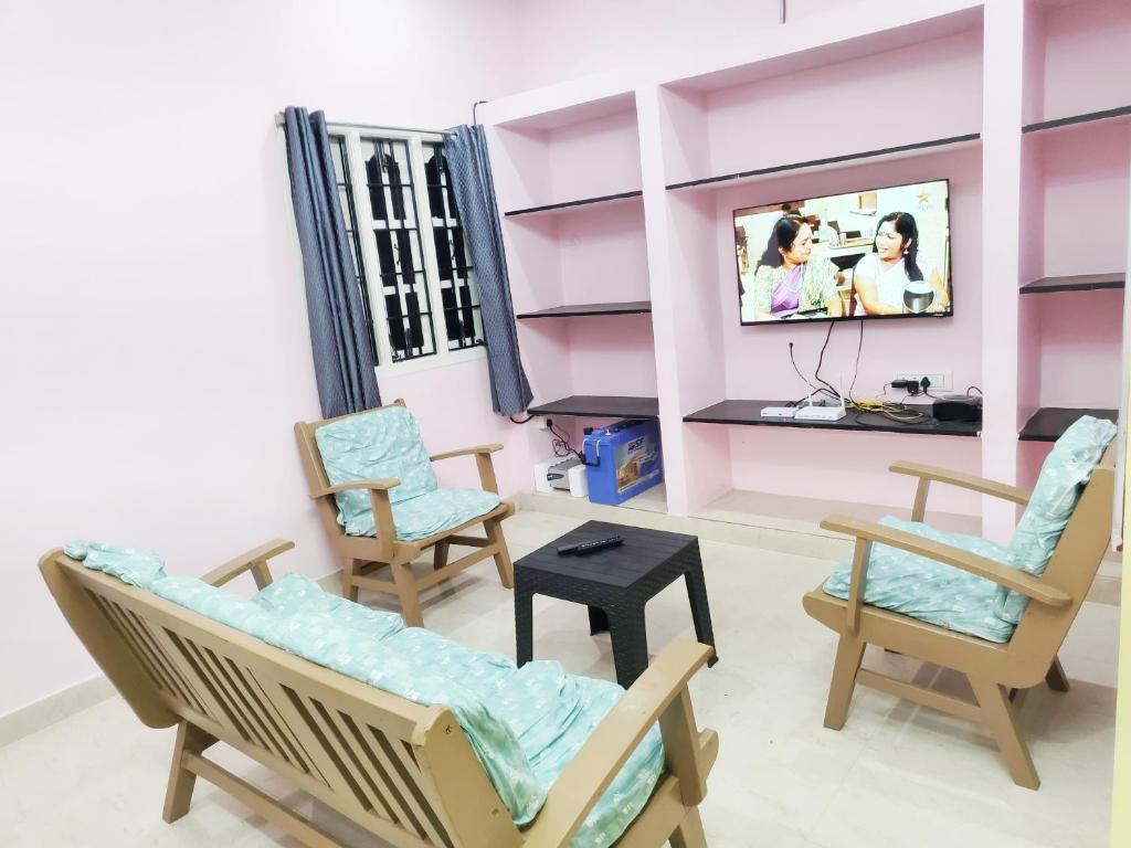 a living room with rocking chairs and a tv at Miracle Stay in Madurai
