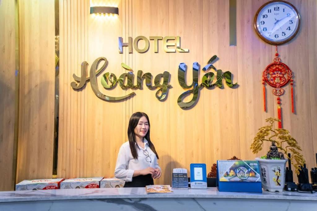 a woman standing behind a counter in a hotel living room at Nhà Nghỉ Hoàng Yến in Cái Răng