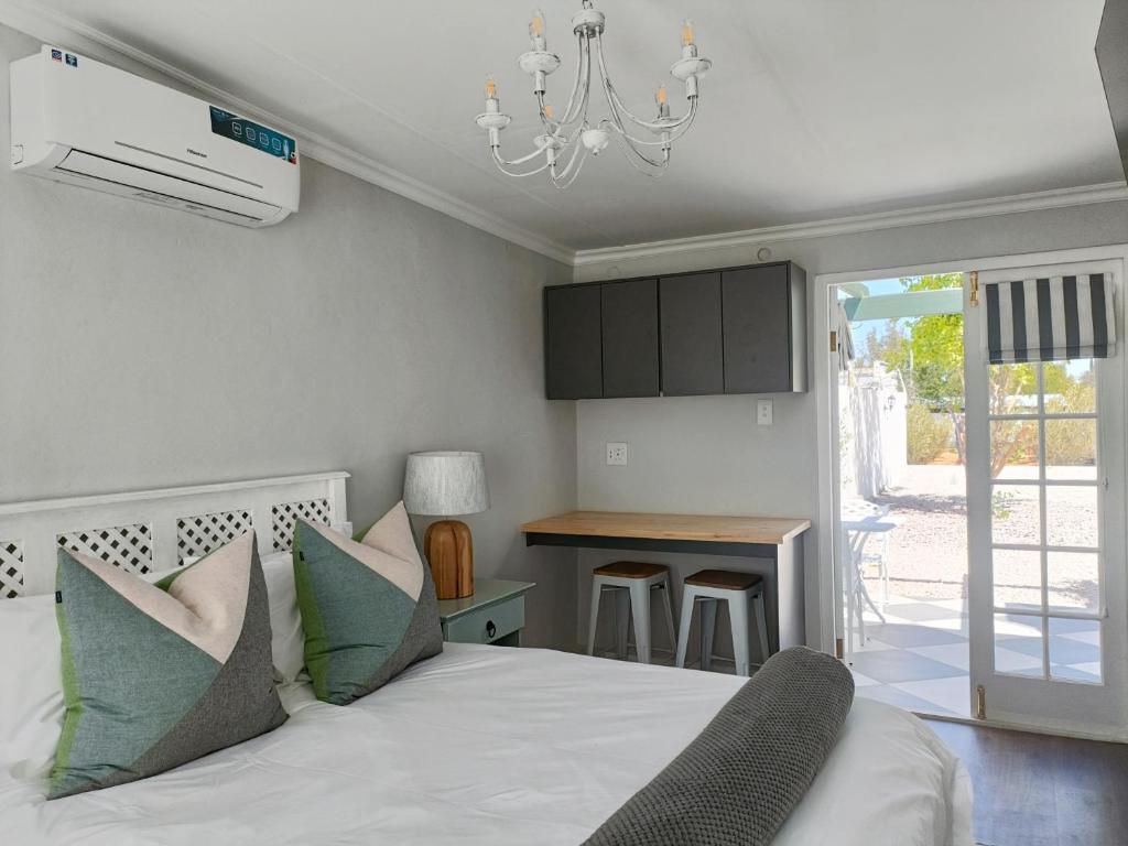 a bedroom with a white bed with a chandelier at Bij De Graaff in Graaff-Reinet