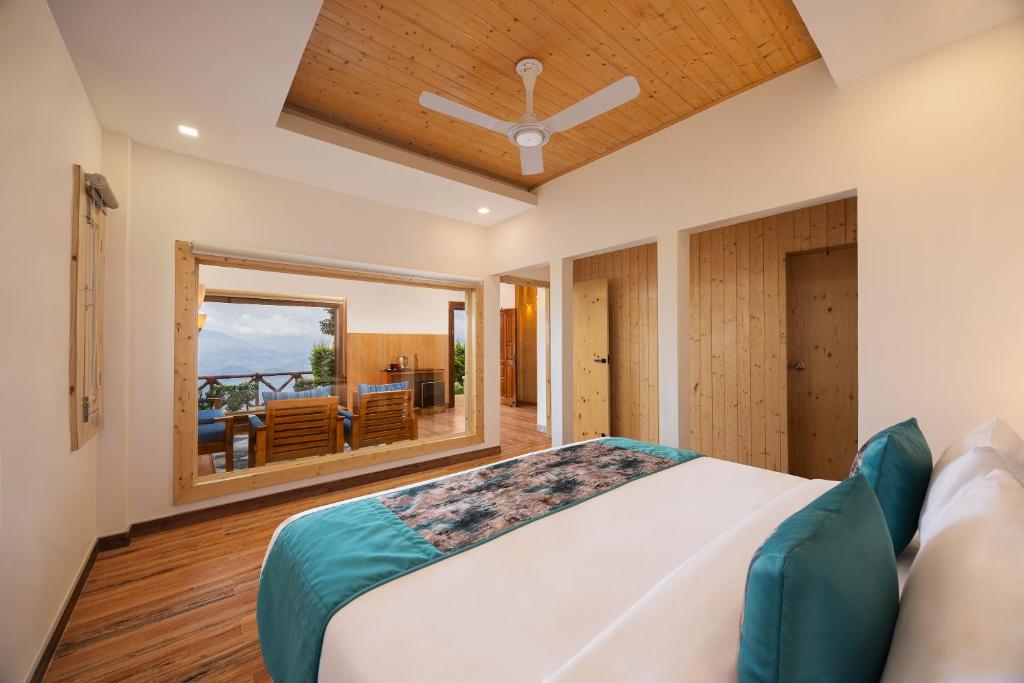 a bedroom with a large bed and a balcony at WelcomHeritage Arka Resort & Spa, Rishikesh in Bijni