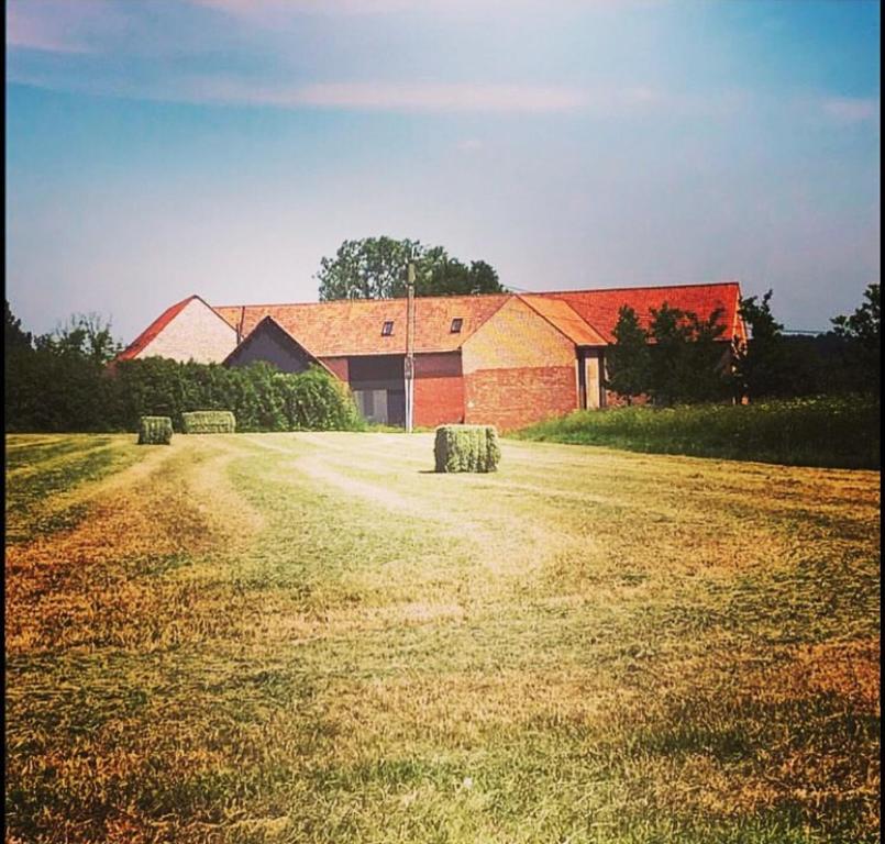 a large building with hay bales in front of a field at Les Pommiers in Ellezelles
