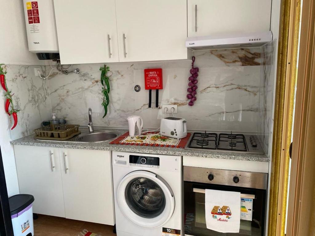 a kitchen with a stove and a washing machine at Vista Clara in Ponta do Sol