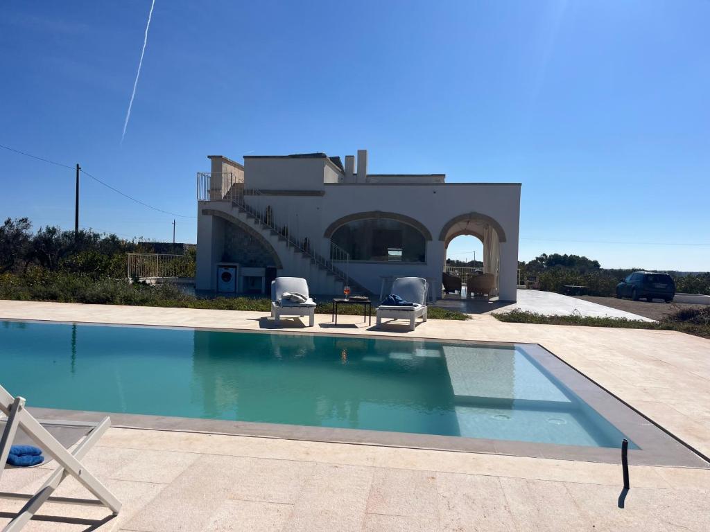 a swimming pool with two chairs and a house at Villa Chiara by salentoltremare in Corsano
