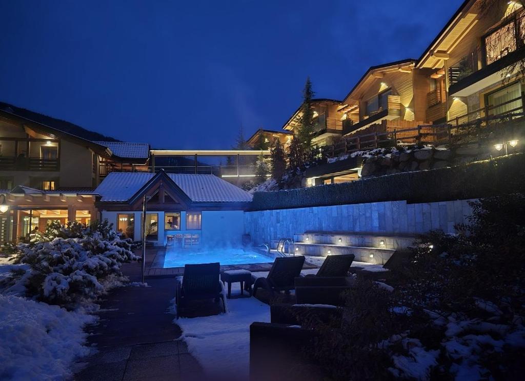een huis met een zwembad in de sneeuw 's nachts bij Boutique Hotel e Chalets Salvadori in Mezzana